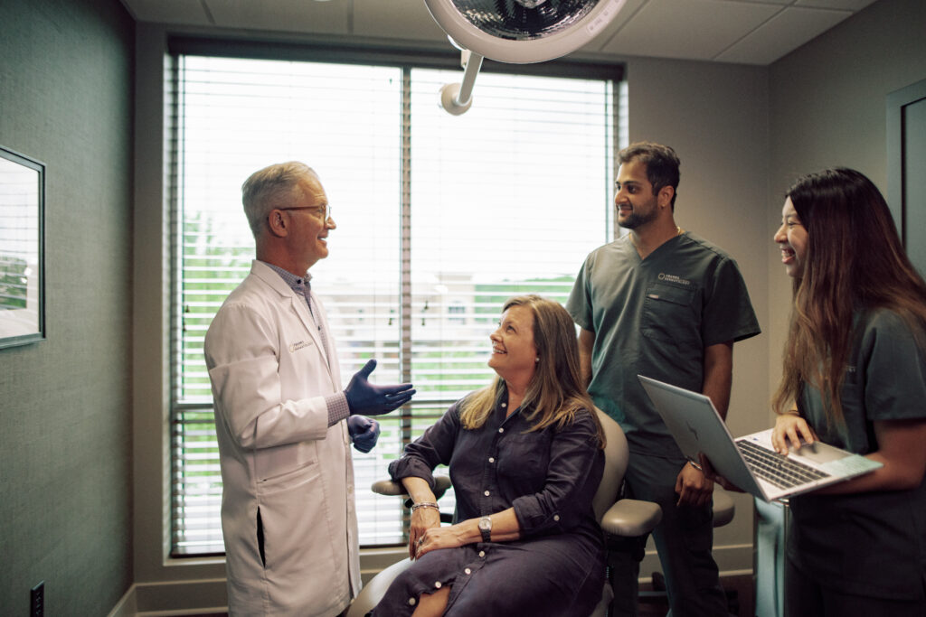 A doctor speaking with a patient and two students.