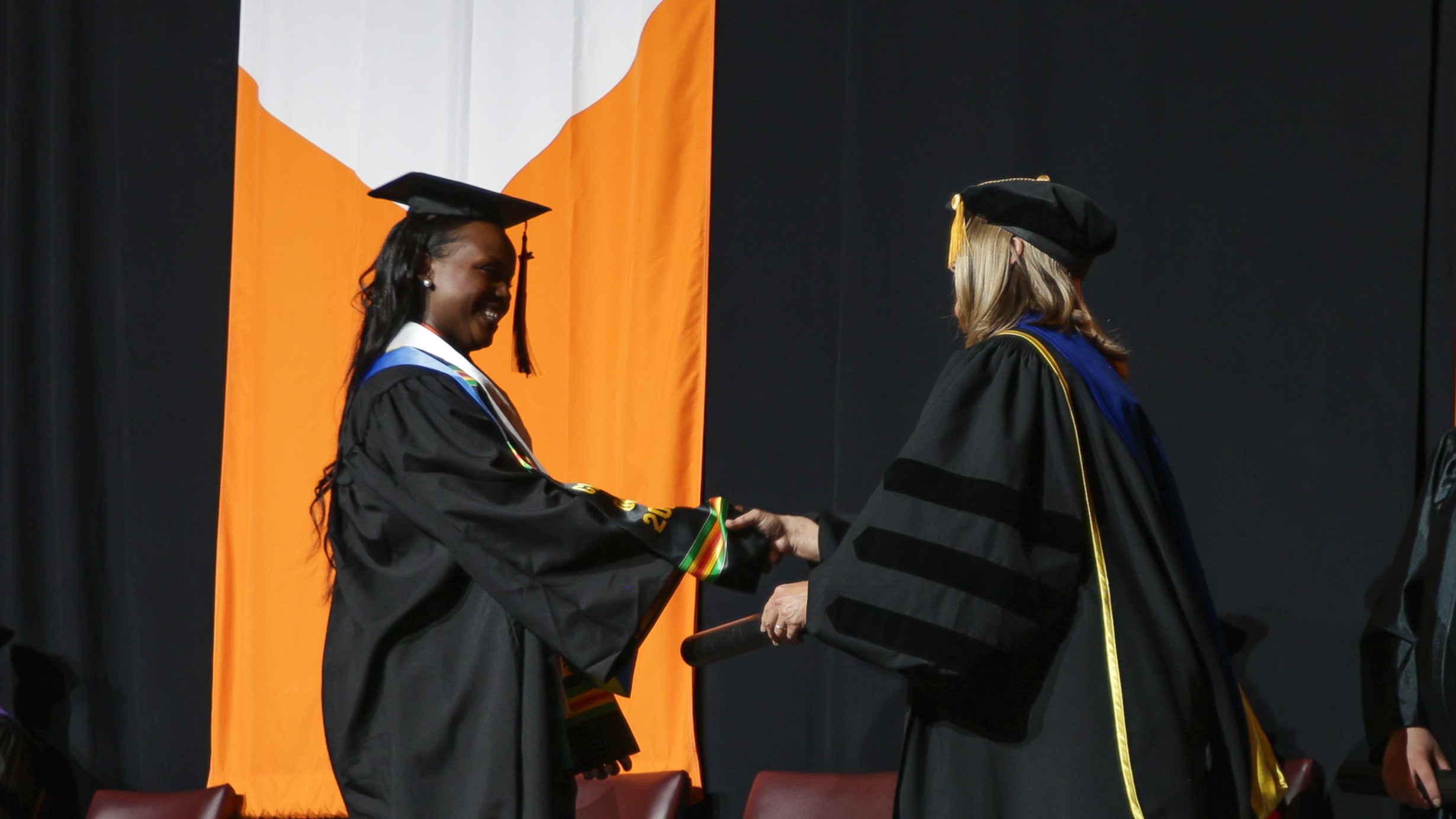 An international student shakes hands with President Karen Petersen at the Commencement Ceremony.