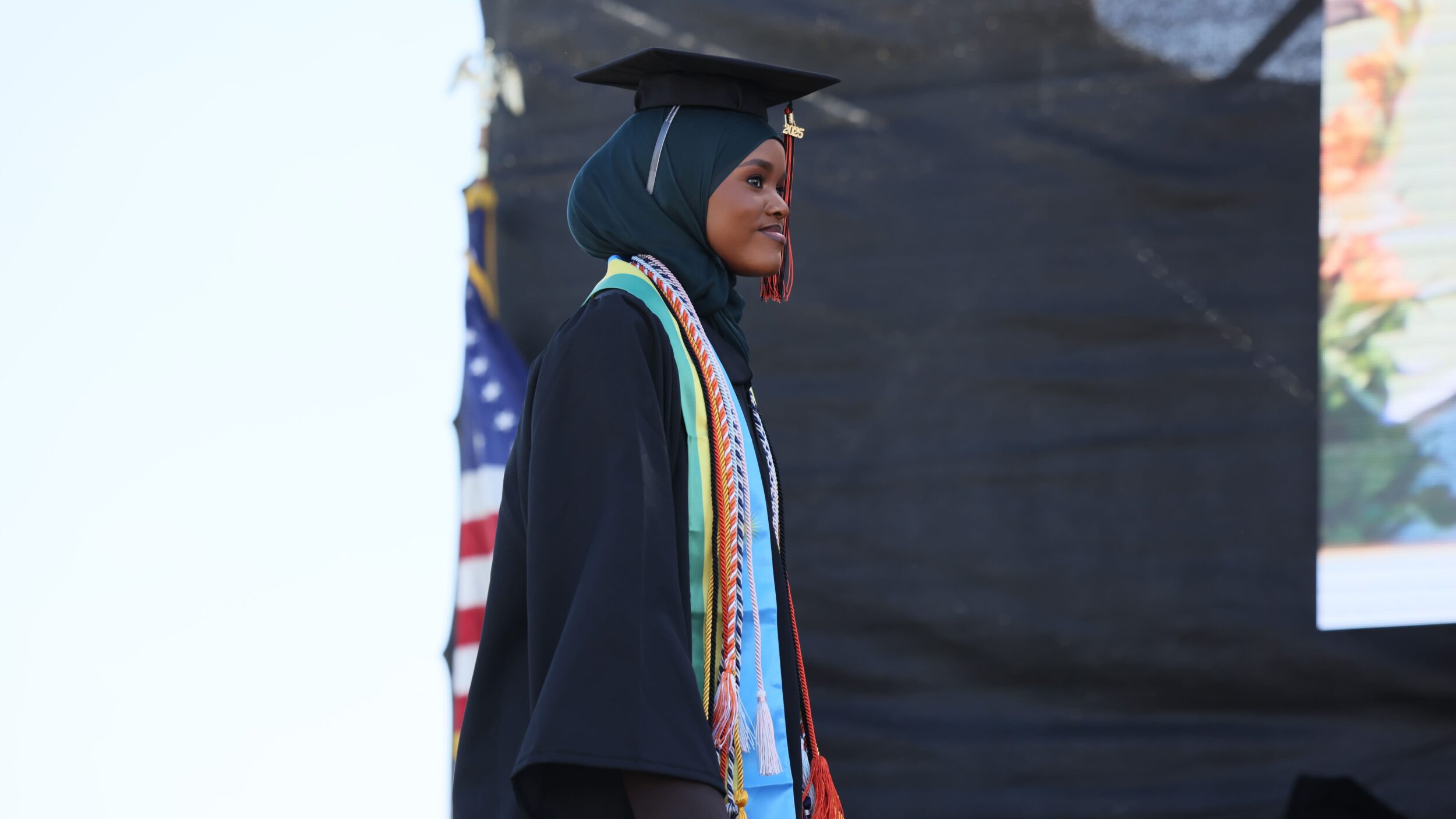 An international student walks across the stage at commencement.