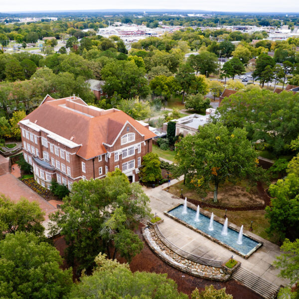 Aerial view of Hendrix College Fountain next to the Donald W. Reynolds Center for Life Sciences building, surrounded by trees on a bright day.