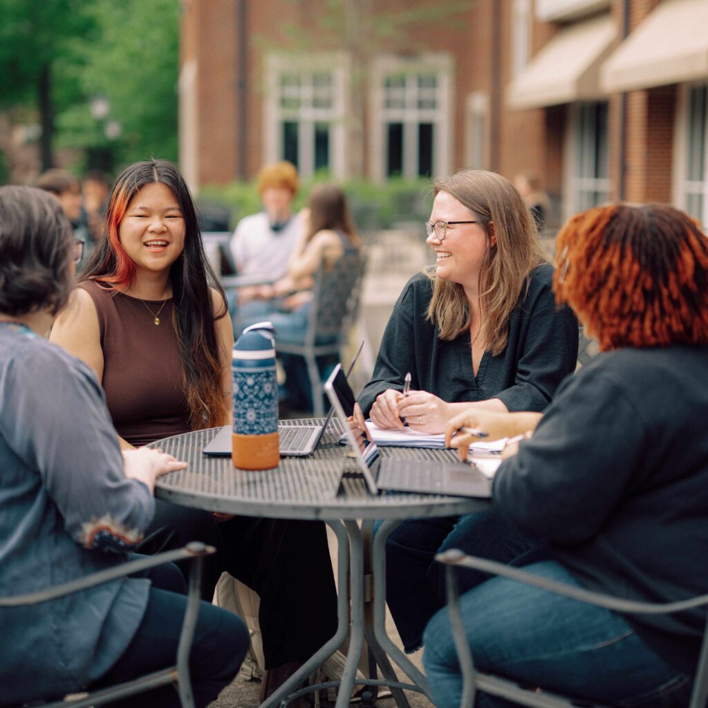 Four people sit around an outdoor table.