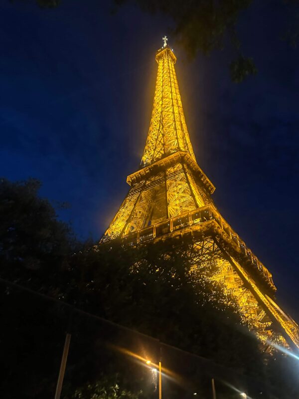 The Eiffel Tower lit with soft yellow lights at night.