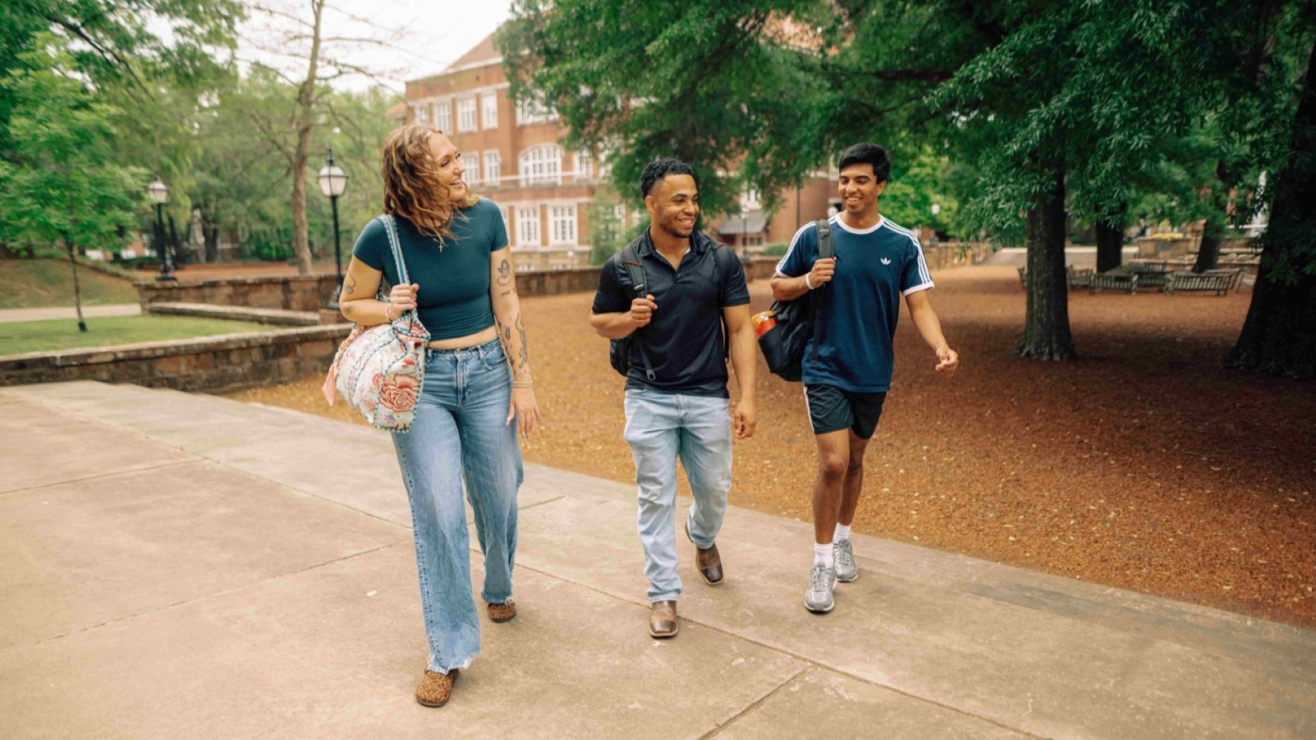 Three Hendrix students walk outside, next to each other, on the stairs leaving the Pecan Court.