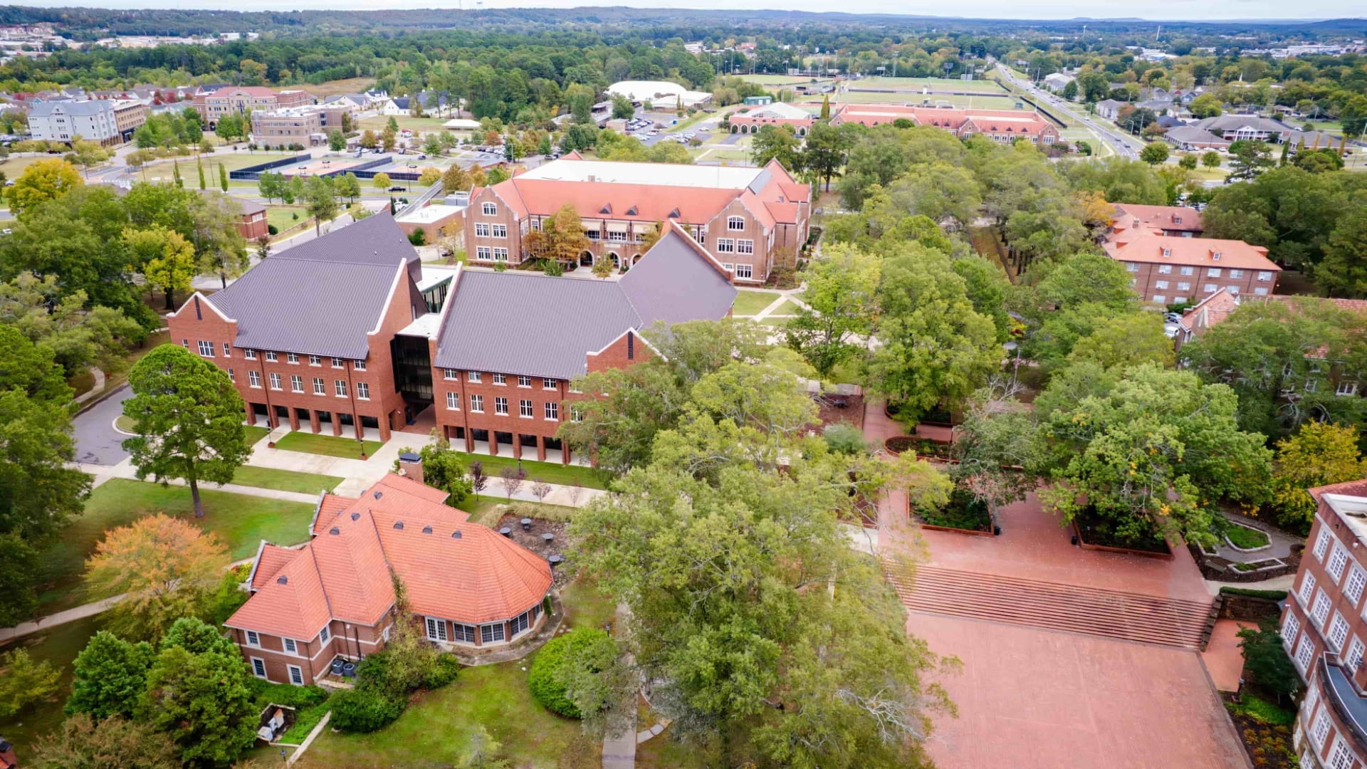 Aerial view of part of Hendrix’s campus showing slanted rooftops, red brick buildings, parking lots, and greenery.