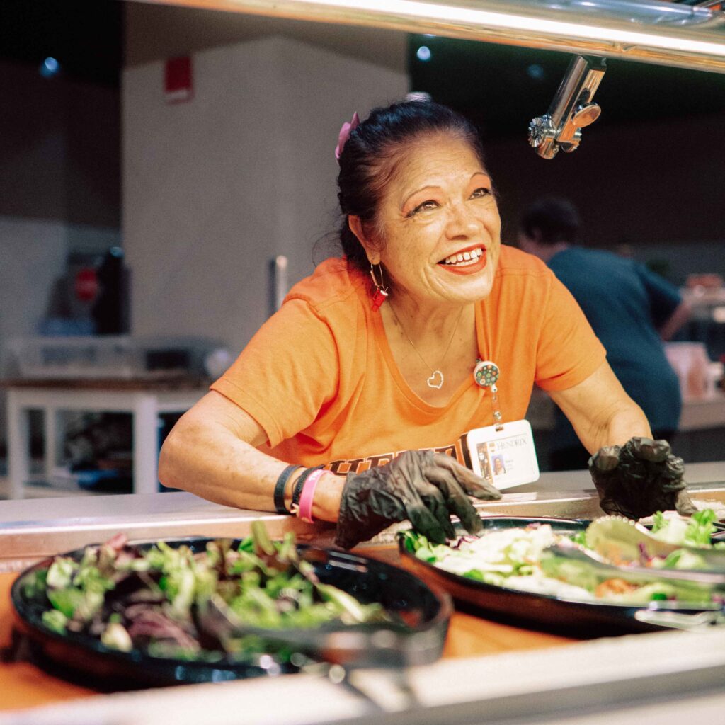 A Hendrix Dining Services worker greets students at the salad bar