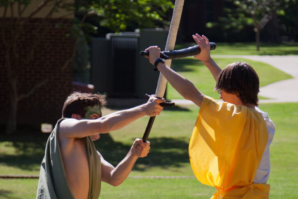 Two students battle with foam swords.