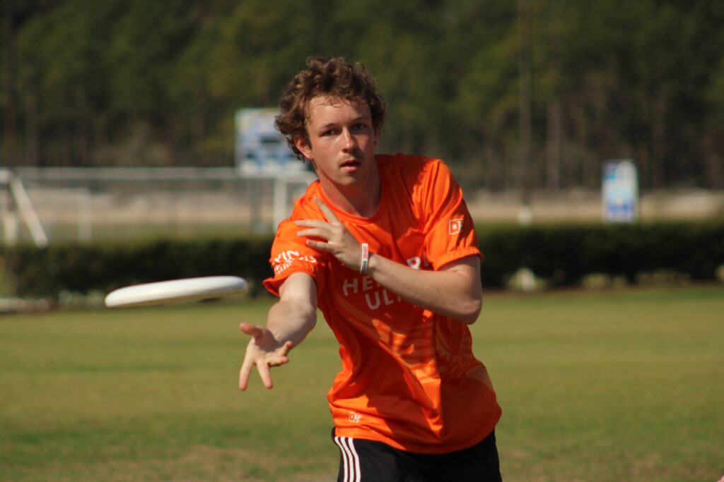 A student in a Hendrix Ultimate Frisbee jersey throws a frisbee.