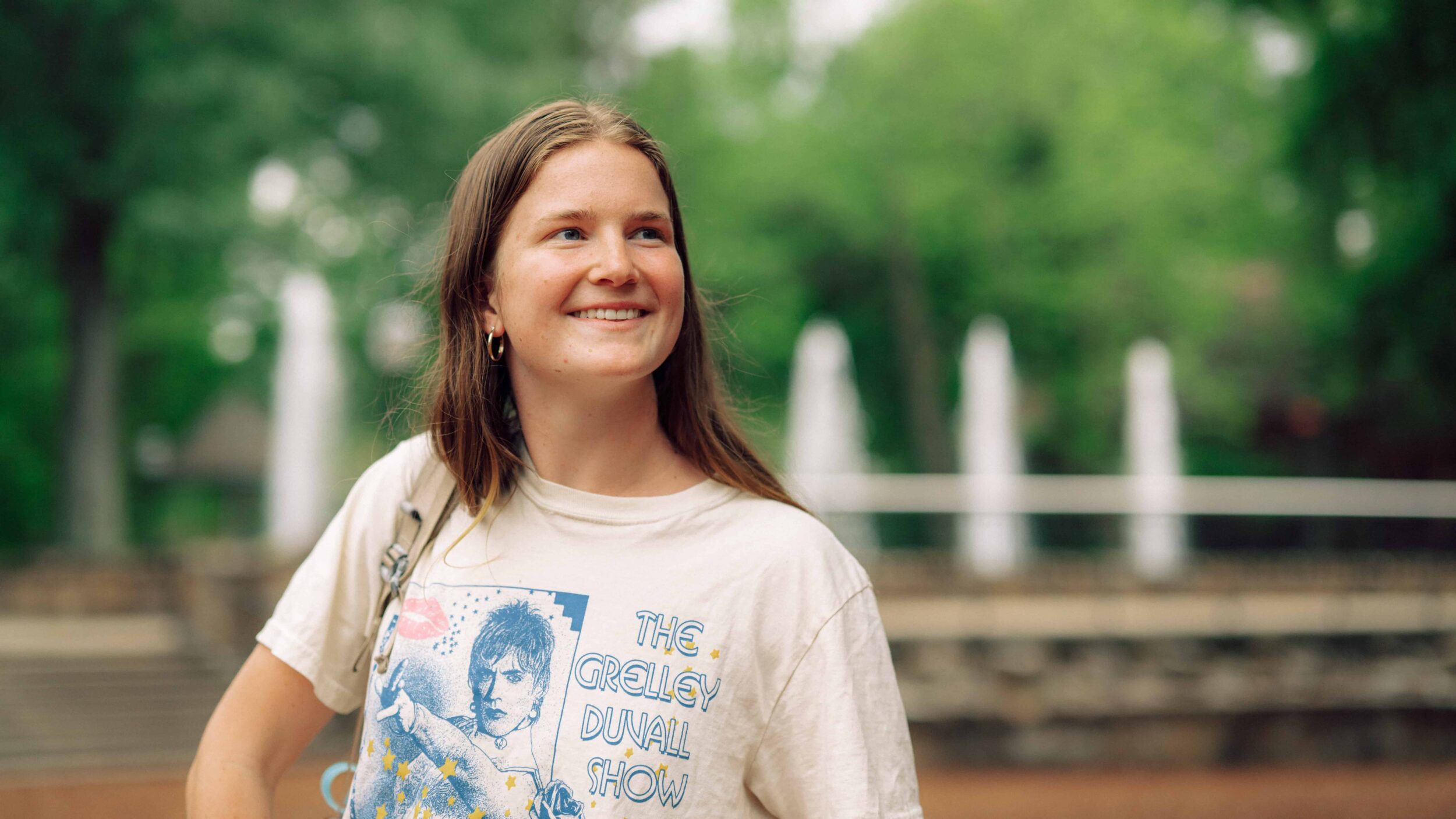 A student stands in front of a fountain.