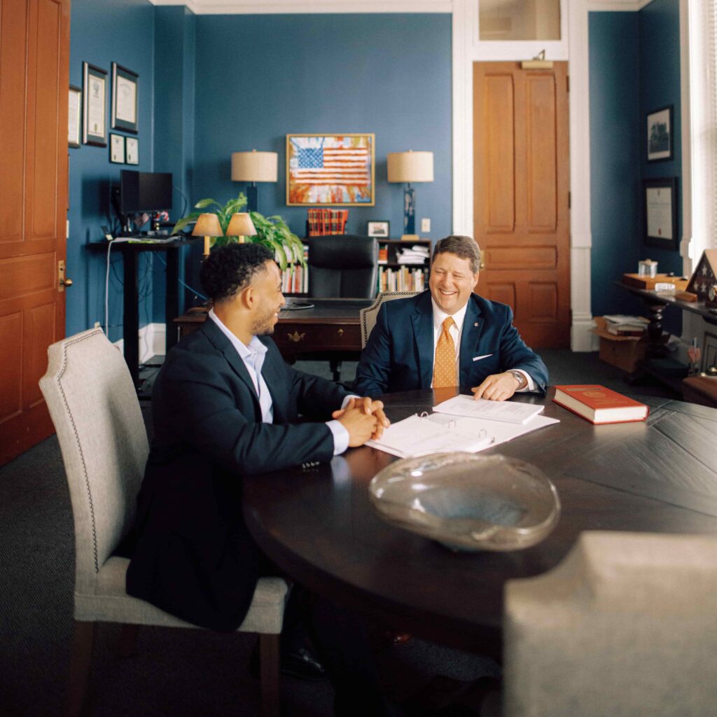 A student and an employer sit together at a table and look over papers.