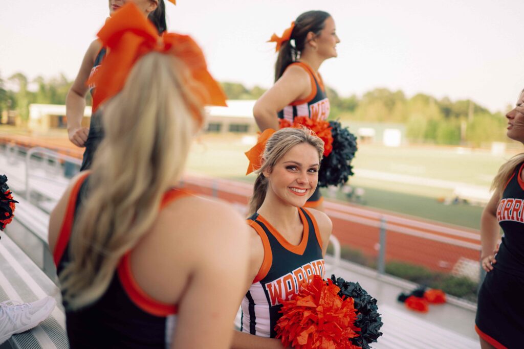 A group of Hendrix cheerleaders gather on the bleaches in the stadium.