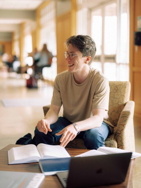 A student sits a table with books.