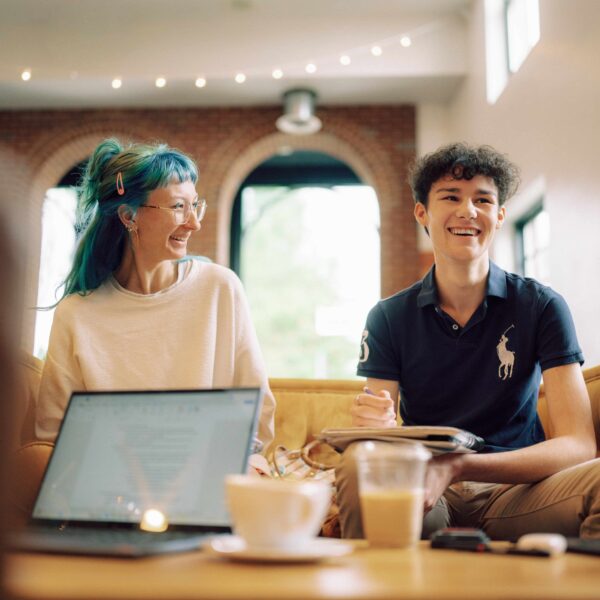 Two people sit at a table laughing while studying.