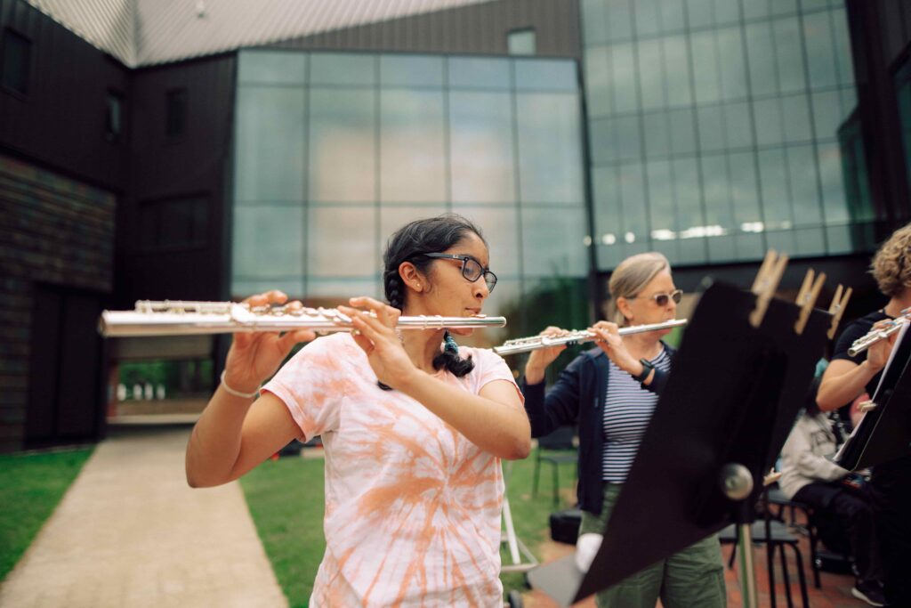 Members of the flute section play in an outdoor rehearsal.
